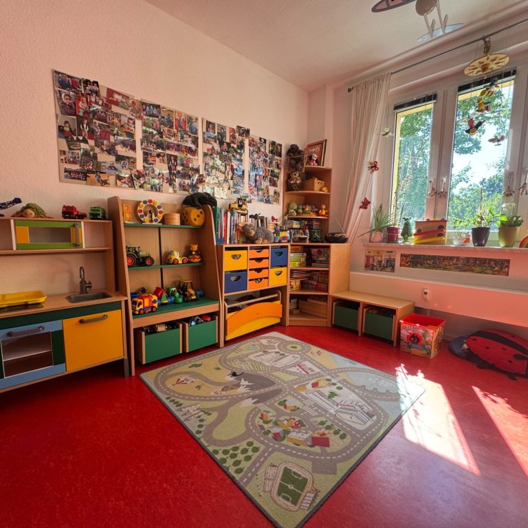 Spielziemmer Bunt eingerichteter Kinderraum mit Spielzeug, Teppich und großen Fenstern.